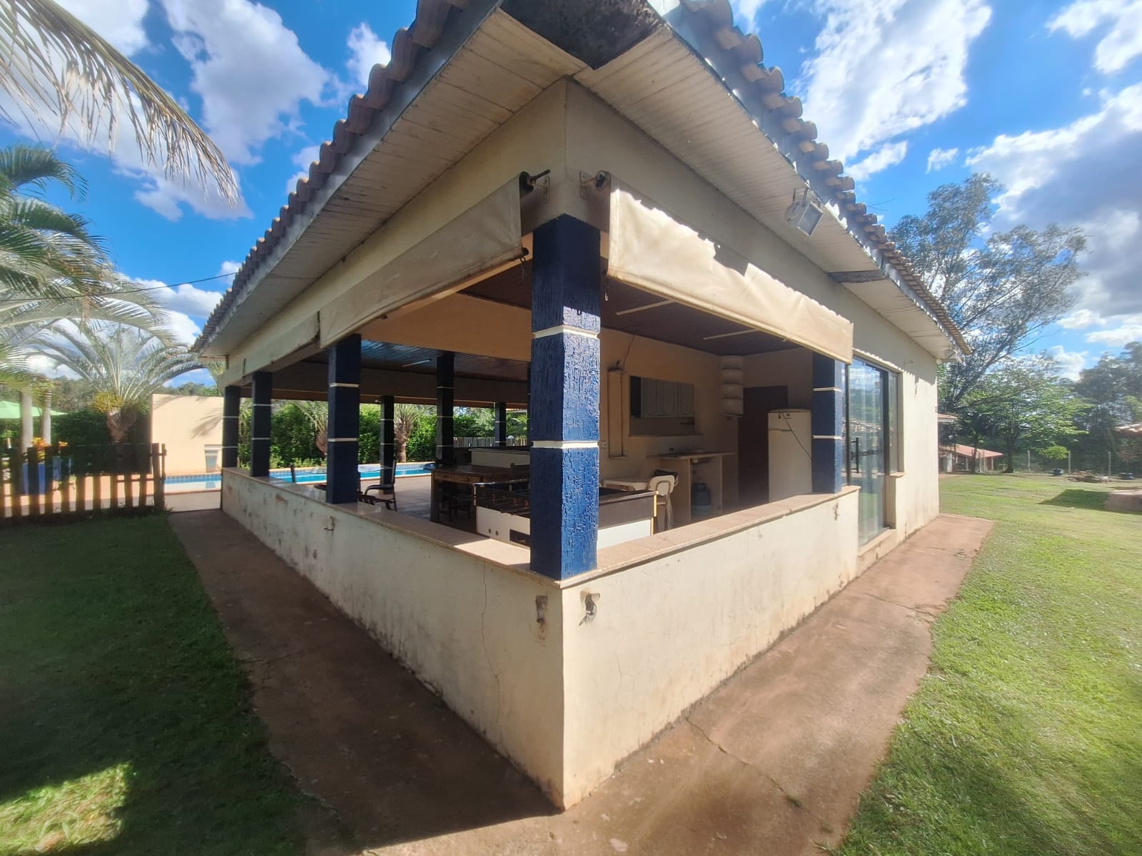 Quiosque coberto com colunas azuis e vista para a piscina
